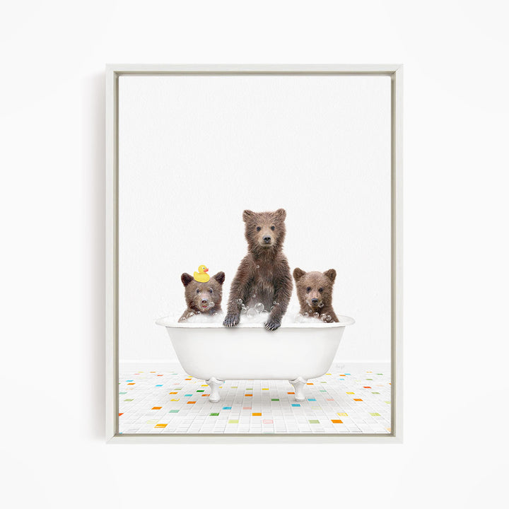 Three adorable brown bears sitting in a white bathtub filled with water, with one bear holding a yellow rubber duck.