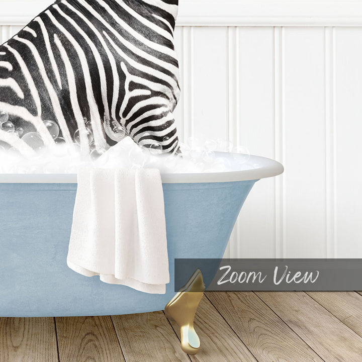 A zebra standing in a blue bathtub filled with bubbles, with a towel hanging on the side and a gold object on the floor.