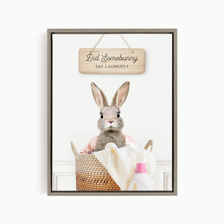 A cute rabbit sitting in a woven laundry basket, with a sign above that says "Did Somebunny Sat Laundry?".