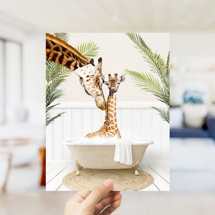 A hand holds up a framed image depicting two giraffes sitting in a bathtub, surrounded by palm leaves.