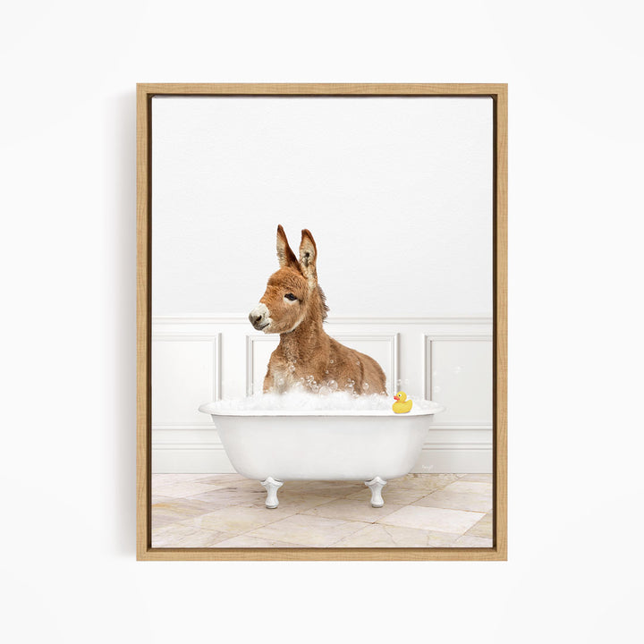 A donkey is sitting in a white bathtub filled with bubbles, with a rubber duck floating in the water.