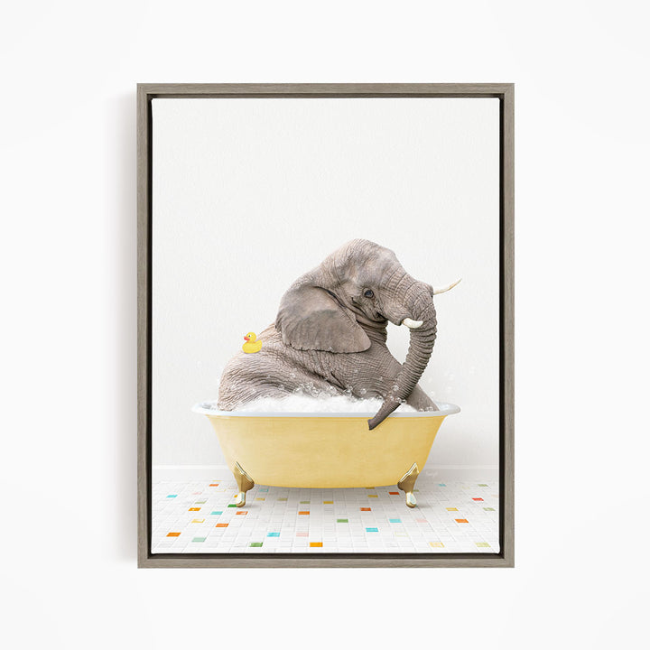 A gray elephant is sitting in a yellow bathtub, with a single yellow rubber duck floating on the water.