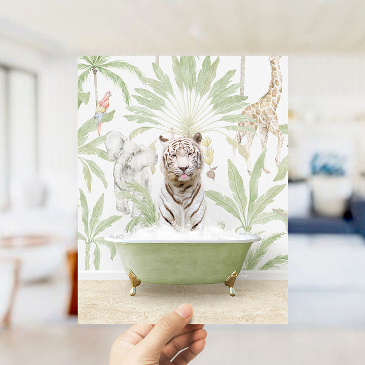 A hand holds up a framed print featuring a tiger sitting in a bathtub surrounded by tropical foliage, including a giraffe and an elephant.