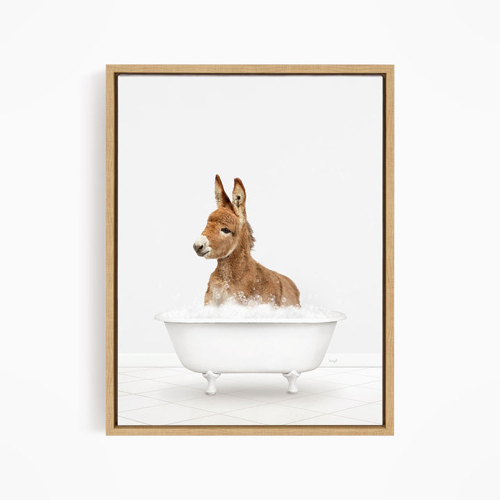 A donkey is sitting in a white bathtub filled with bubbles, looking directly at the camera.