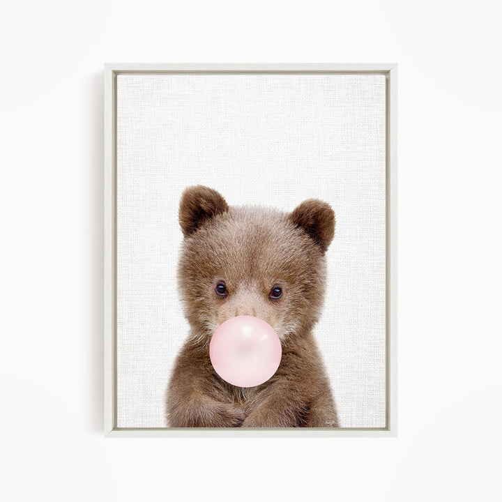 A cute brown bear is blowing a bubble with a pink bubble gum bubble.
