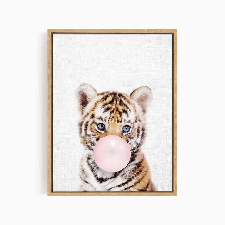 A young tiger cub blowing a bubble with a pink bubble gum bubble.