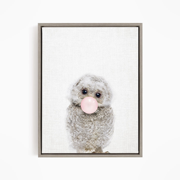 A cute gray owl with large eyes is blowing a bubble with a pink bubble gum bubble.