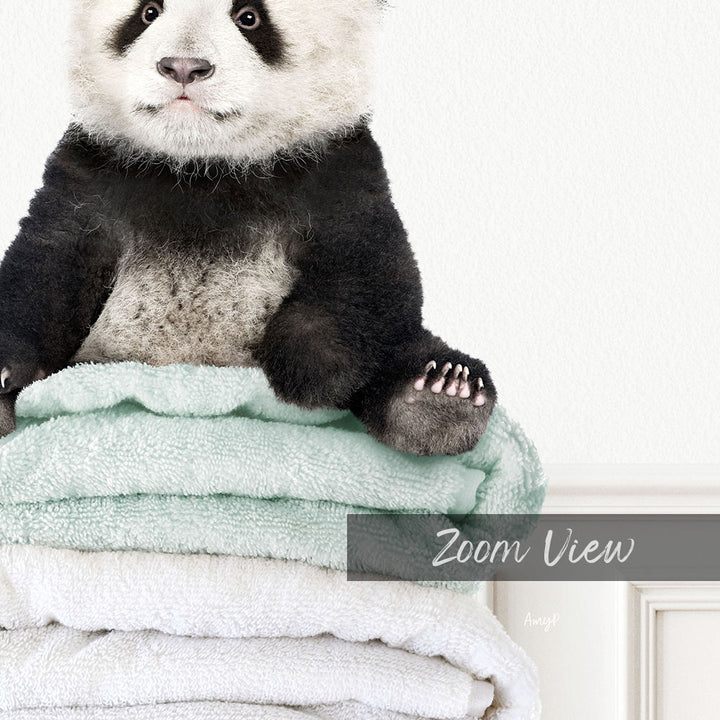 A panda bear sitting on a stack of light blue towels.