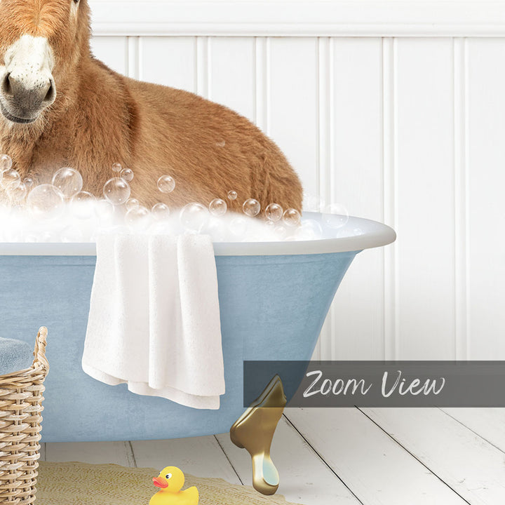 A brown horse is sitting in a blue bathtub filled with bubbles, surrounded by a yellow rubber duck and a white towel.