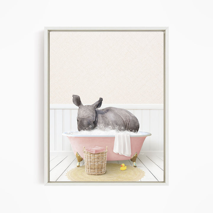 A rhinoceros is sitting in a pink bathtub filled with water, surrounded by a yellow rubber duck and a wicker basket.