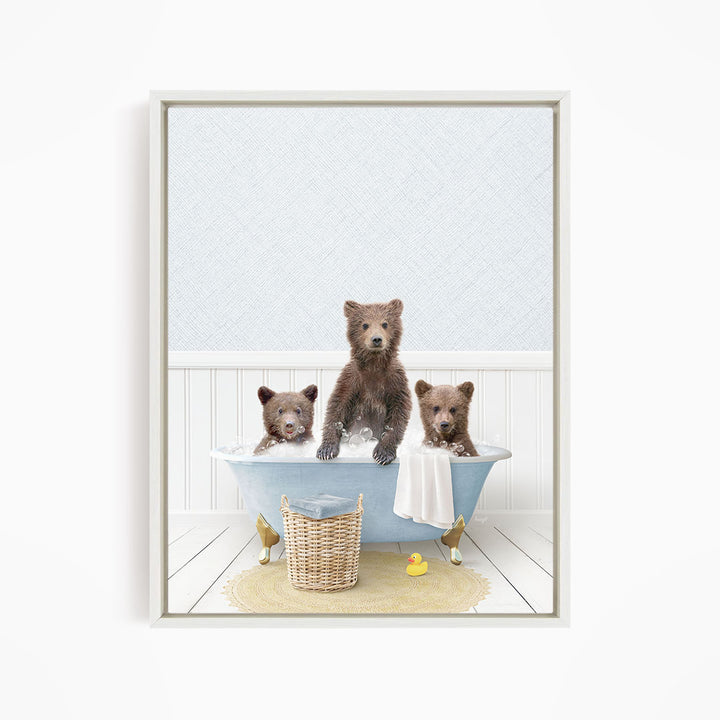 A framed image depicting three brown bears sitting in a blue bathtub, with a yellow rubber duck floating in the water.
