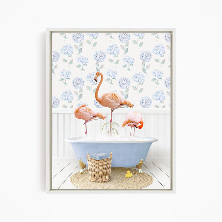 A framed image depicting three pink flamingos standing in a blue bathtub, with a blue and white floral patterned wall behind them.