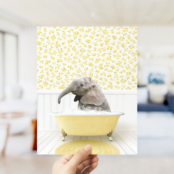 A small gray elephant is sitting in a yellow bathtub filled with water, surrounded by a yellow and white patterned wallpaper.