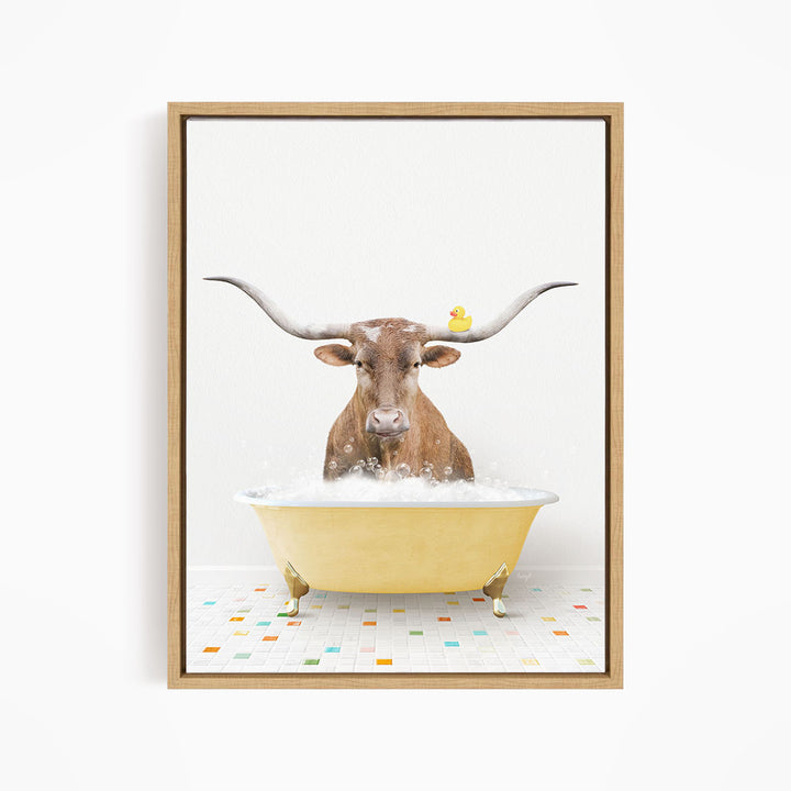 A brown cow with large horns is sitting in a yellow bathtub filled with bubbles, with a yellow rubber duck perched on its head.