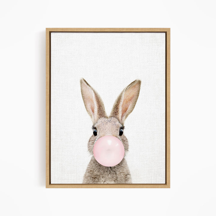 A cute bunny with large ears blowing a pink bubblegum bubble.