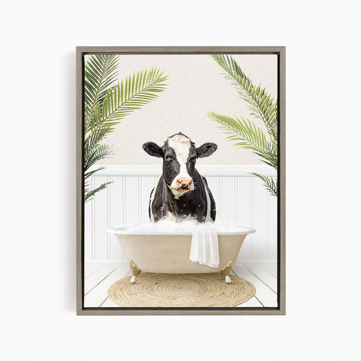 A black and white cow is sitting in a white bathtub filled with water, surrounded by green palm leaves.