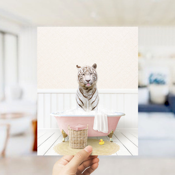 A white tiger sitting in a pink bathtub filled with bubbles, surrounded by a yellow rubber duck and a white towel.