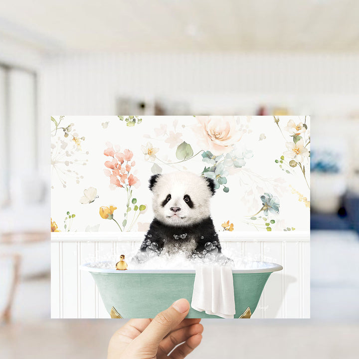 A hand is holding up a framed image of a panda sitting in a bathtub filled with bubbles, surrounded by a floral pattern.