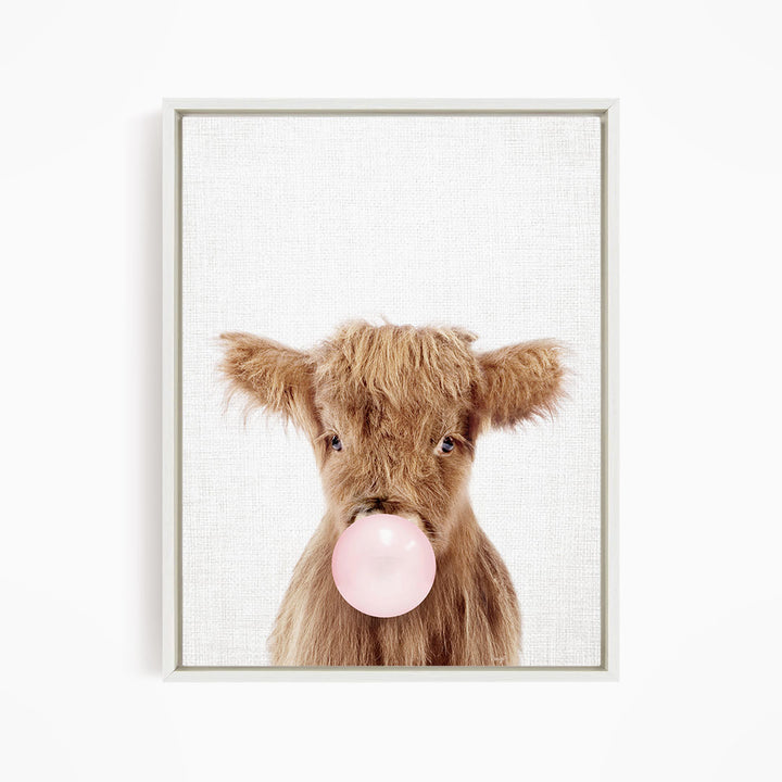 A brown cow with shaggy hair is blowing a pink bubble with its mouth, creating a playful and whimsical scene.