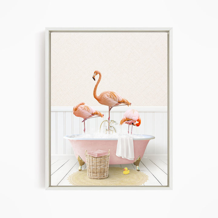 A framed image depicting three pink flamingos standing in a pink bathtub, with a basket of bath toys and a yellow rubber duck nearby.