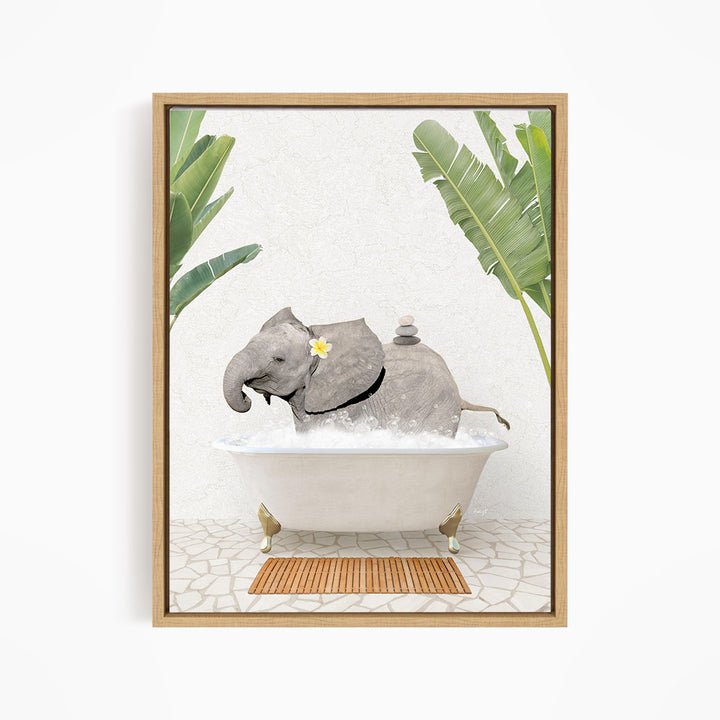 A framed image depicting a gray elephant sitting in a white bathtub, surrounded by green leaves and a wooden mat on the floor.