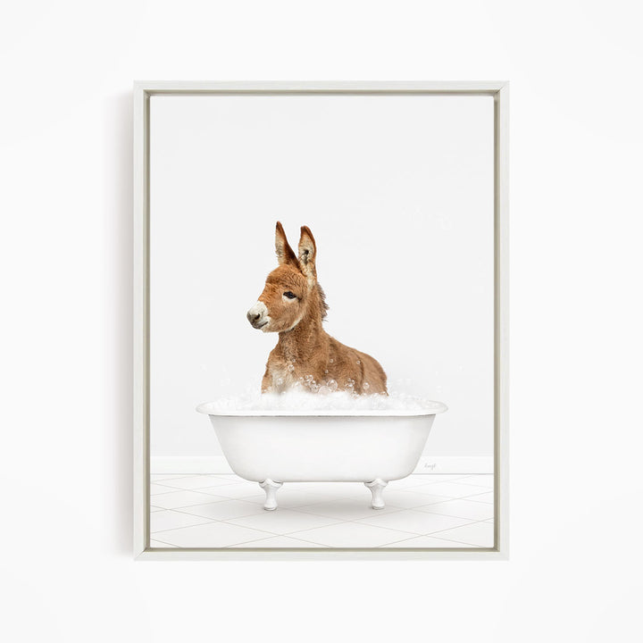 A donkey is sitting in a white bathtub filled with bubbles, looking directly at the camera.