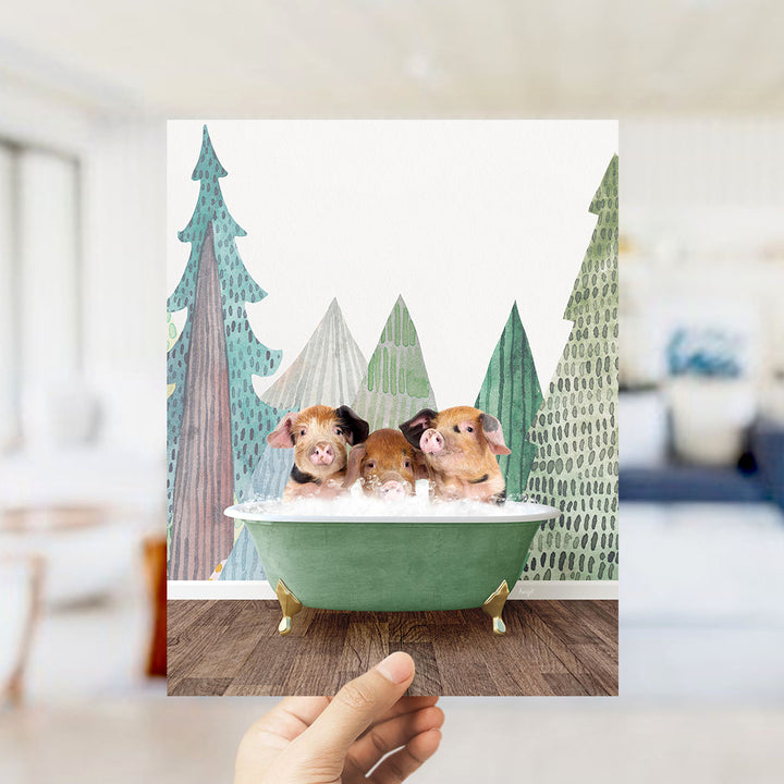 A hand is holding up a framed image of three adorable pigs sitting in a green bathtub, surrounded by a forest-themed background.