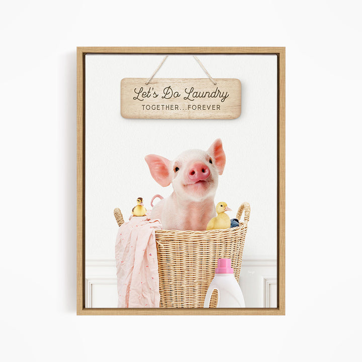 A cute pig sitting in a wicker basket filled with toys, with a wooden sign above that says "Let's Do Laundry Together Forever".