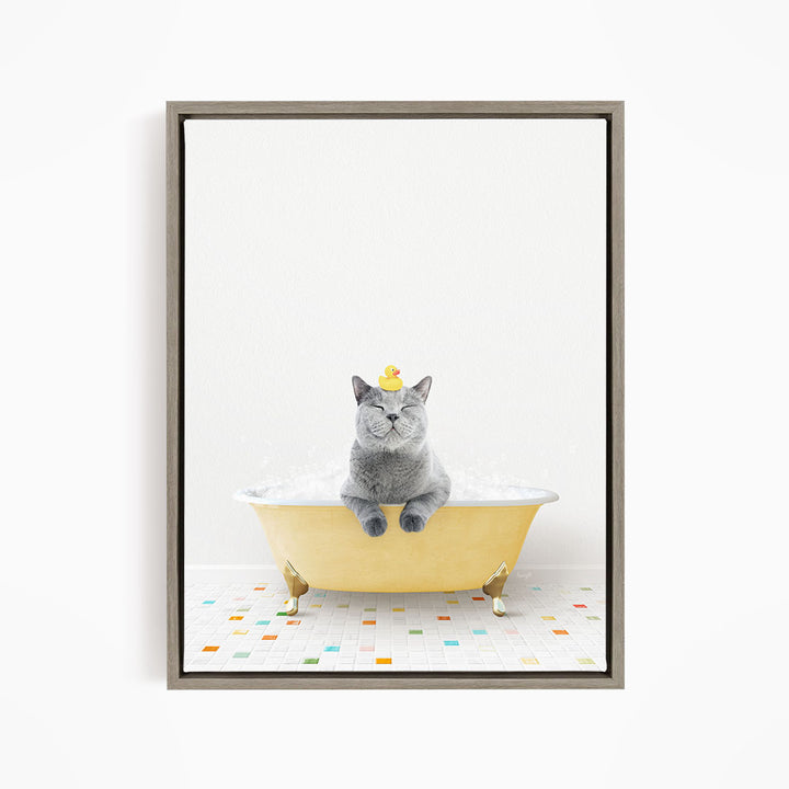 A gray cat sitting in a yellow bathtub, with a rubber duck on its head, and a colorful tiled floor in the background.