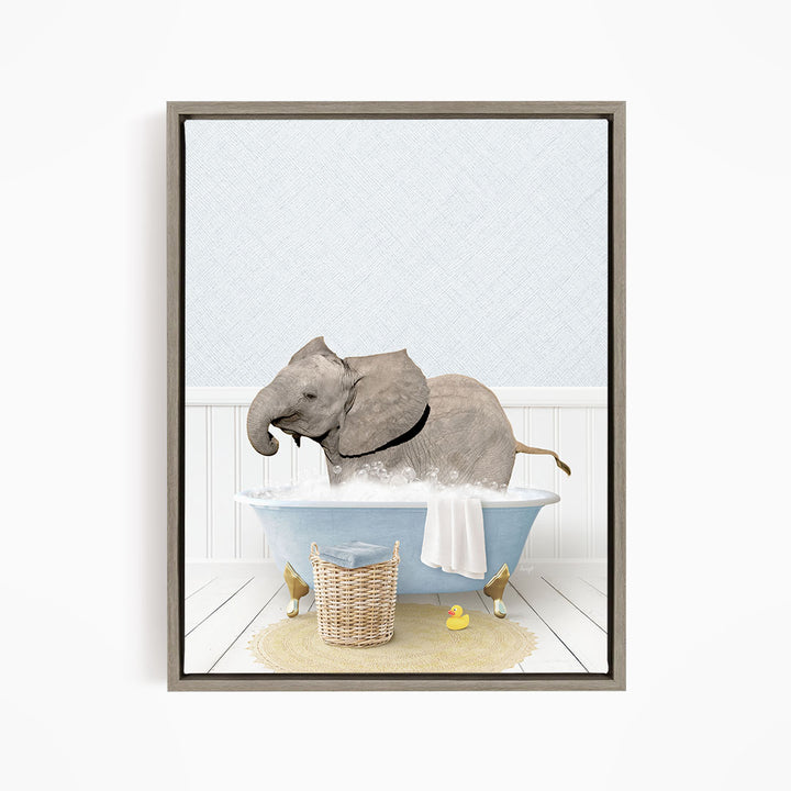 A gray elephant is sitting in a blue bathtub filled with water, surrounded by a yellow rubber duck and a basket.