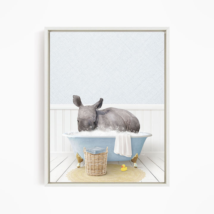 A rhinoceros is sitting in a blue bathtub filled with water, surrounded by a yellow rubber duck and a basket.