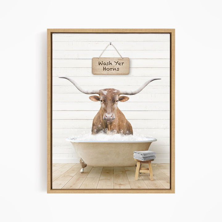 A framed image depicting a bull with large horns sitting in a bathtub, with a sign above that says "Wash Yer Horns".