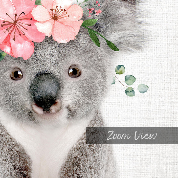 A close-up of a koala bear with a floral headpiece on its head, set against a white background.