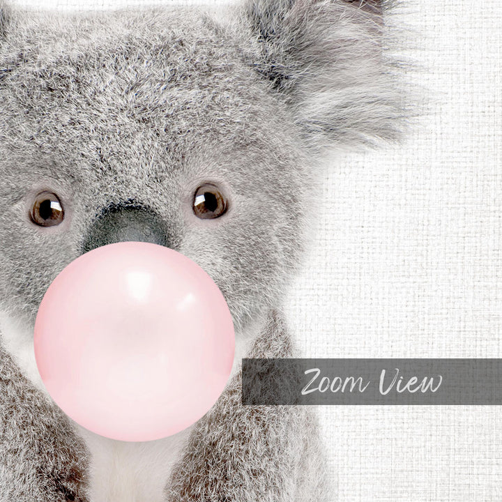 A close-up of a koala bear blowing a pink bubble with its mouth, as if blowing a bubble gum bubble.