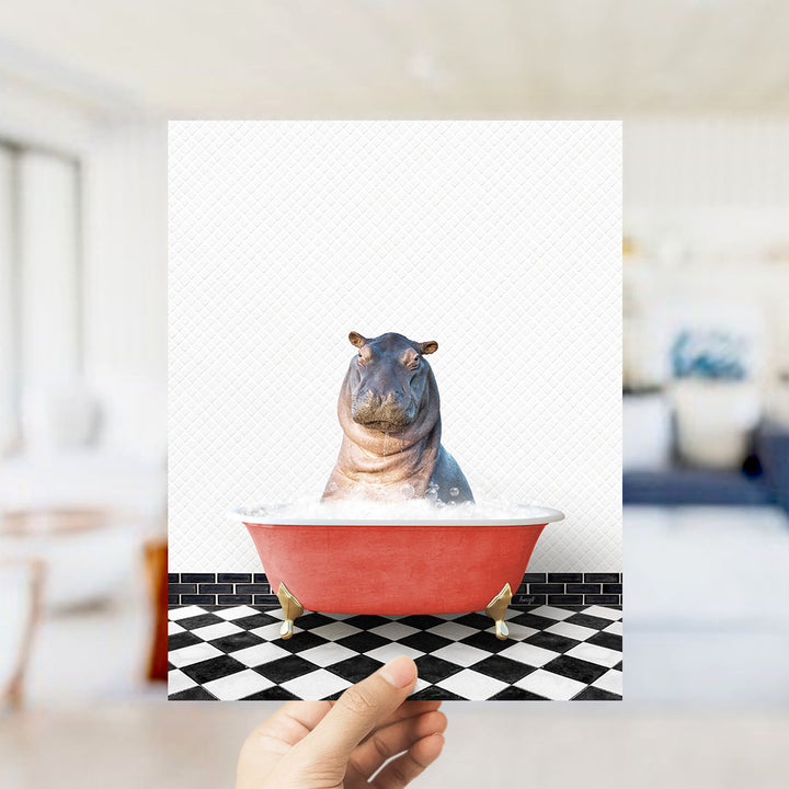 A hand holds up a framed image of a hippopotamus sitting in a red bathtub, surrounded by a black and white checkered floor.