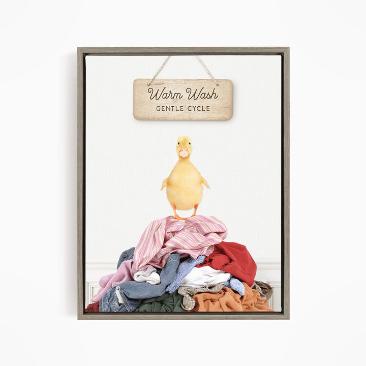 A yellow duck standing on a pile of clothes, with a wooden sign above that reads "Warm Wash Gentle Cycle".