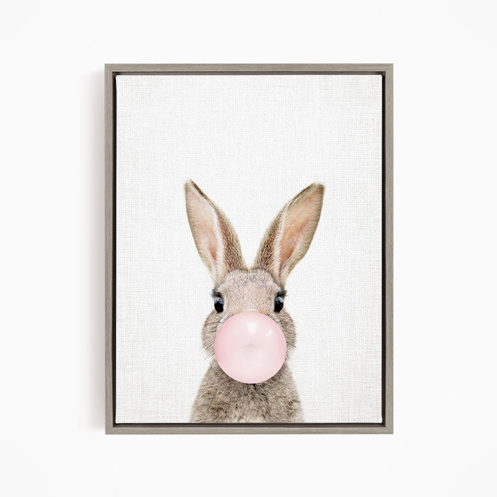 A cute bunny with large ears blowing a bubble with a pink bubblegum bubble.