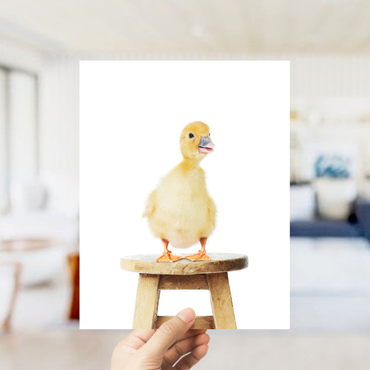A small yellow duck standing on a wooden stool.