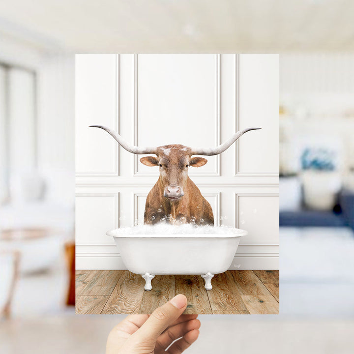 A brown cow with long horns is sitting in a white bathtub filled with bubbles, creating a whimsical and humorous scene.