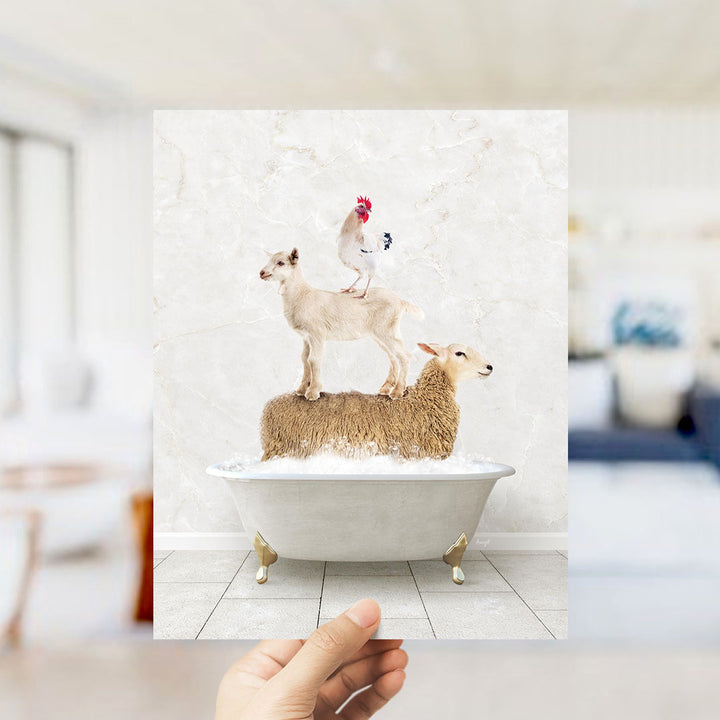 A hand holds up a framed image depicting a goat standing on a sheep's back in a bathtub, with a rooster perched on top of the sheep.