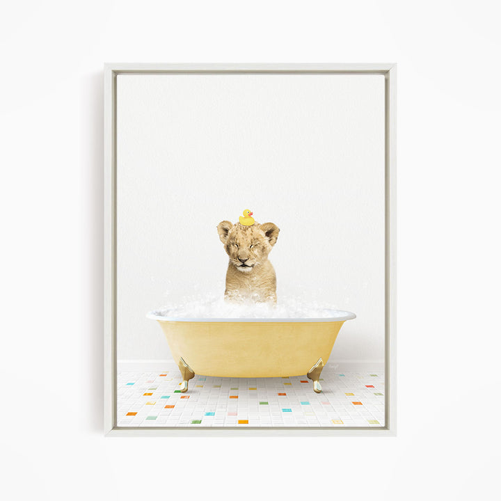 A young lion cub sitting in a yellow bathtub filled with bubbles, with a rubber duck perched on its head.
