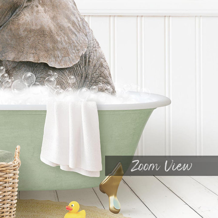 A large elephant is sitting in a green bathtub filled with bubbles, surrounded by a yellow rubber duck and a towel.