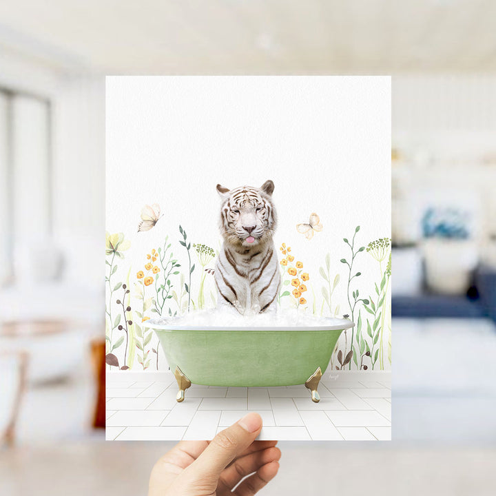 A hand holds up a framed image of a tiger sitting in a green bathtub, surrounded by flowers and butterflies.