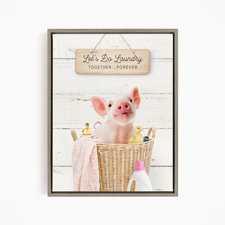 A cute pig sitting in a wicker basket filled with rubber ducks, accompanied by a wooden sign that reads "Let's Do Laundry Together Forever".