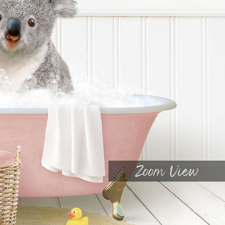 A koala bear sitting in a pink bathtub filled with bubbles, surrounded by a yellow rubber duck and a white basket.