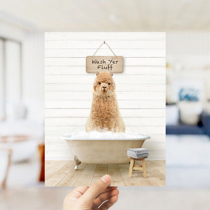 A hand holds up a framed image of a fluffy brown dog sitting in a bathtub filled with bubbles, with a sign above that says "Wash Your Fluff".