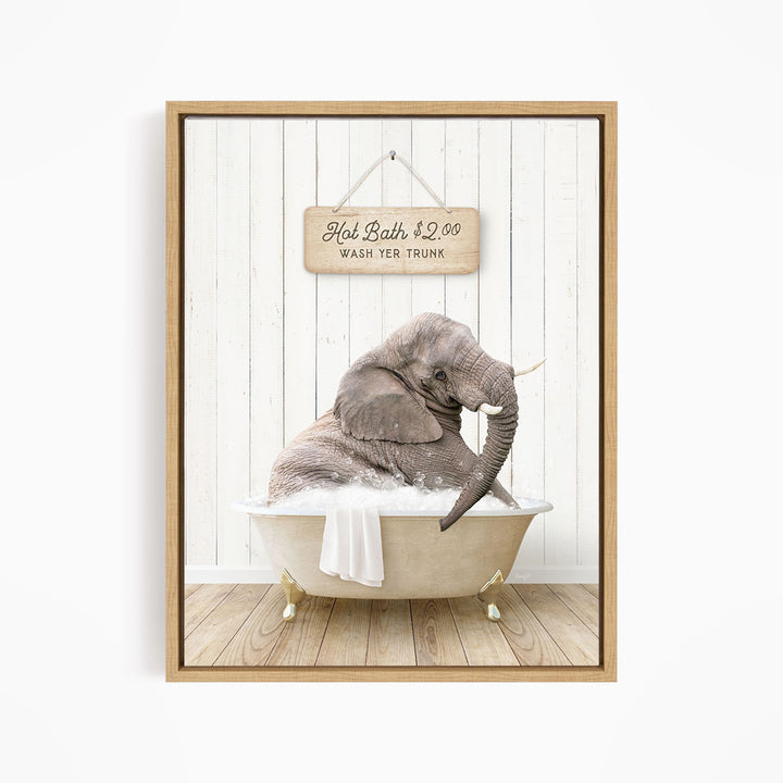 A gray elephant is sitting in a white bathtub filled with water, with a wooden sign above it that reads "Hot Bath $2.00 WASH YER TRunk".