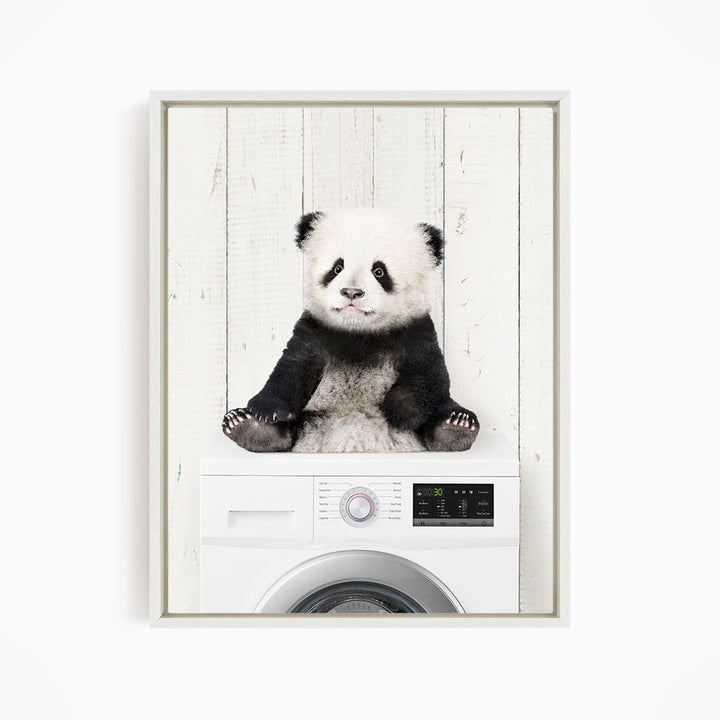 A panda bear sitting on top of a washing machine.
