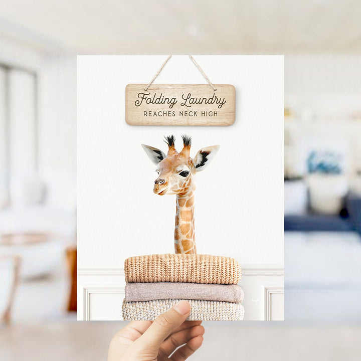 A hand holding a sign that says "Folding Laundry Reaches Neck High" above a stack of folded towels.