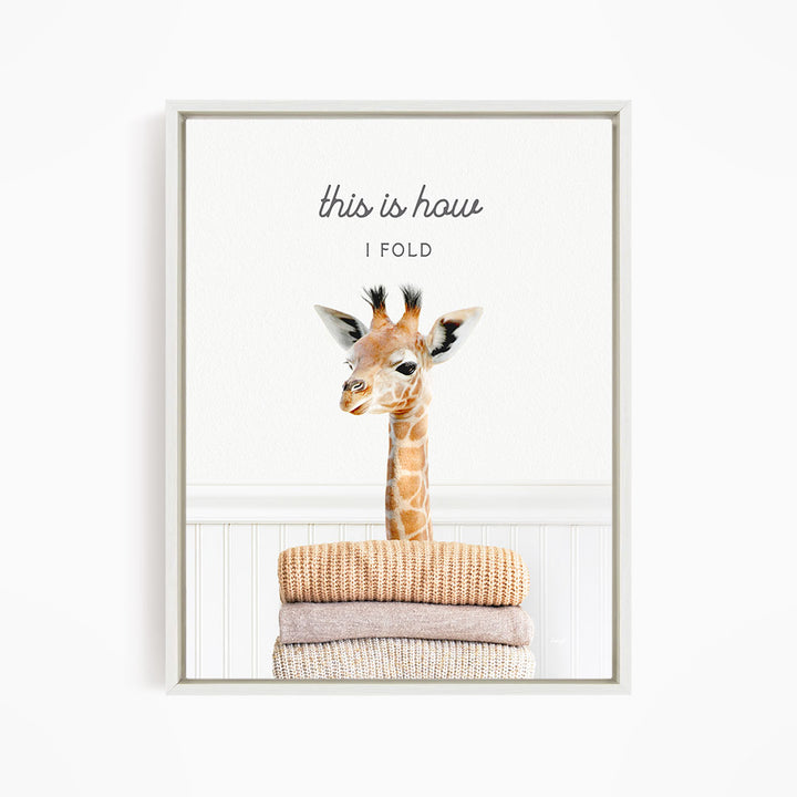 A giraffe standing on a stack of folded blankets, with the text "this is how I fold" written above the image.